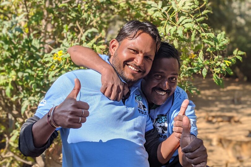 Two TOLFA staff looking at camera, smiling with thumbs up