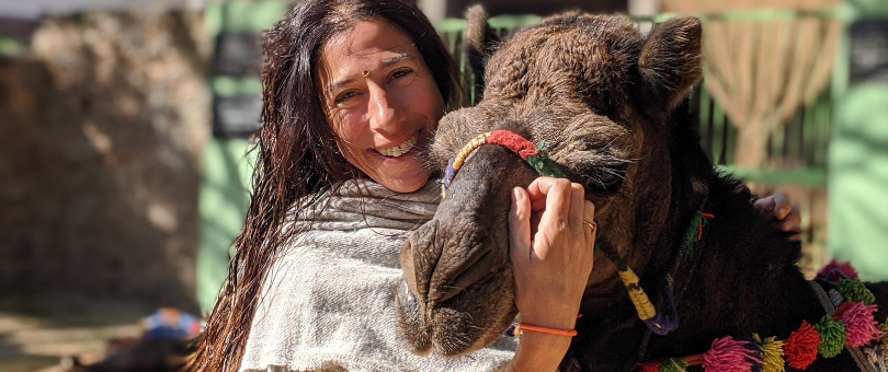 A brunette woman hugging the camel Suraksha